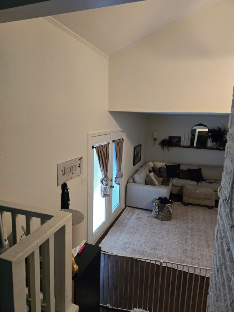 Entry door with curtain and interior wall space near staircase railing