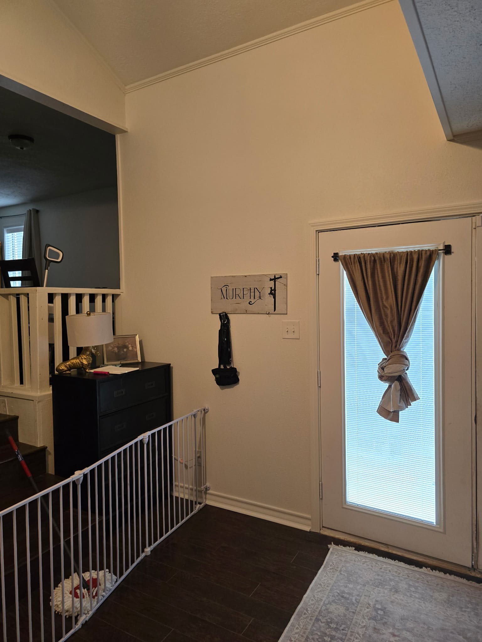 Entry door with curtain and interior wall space near staircase railing
