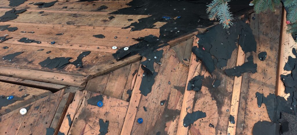 Damaged roof decking boards requiring repair before installing new shingles.