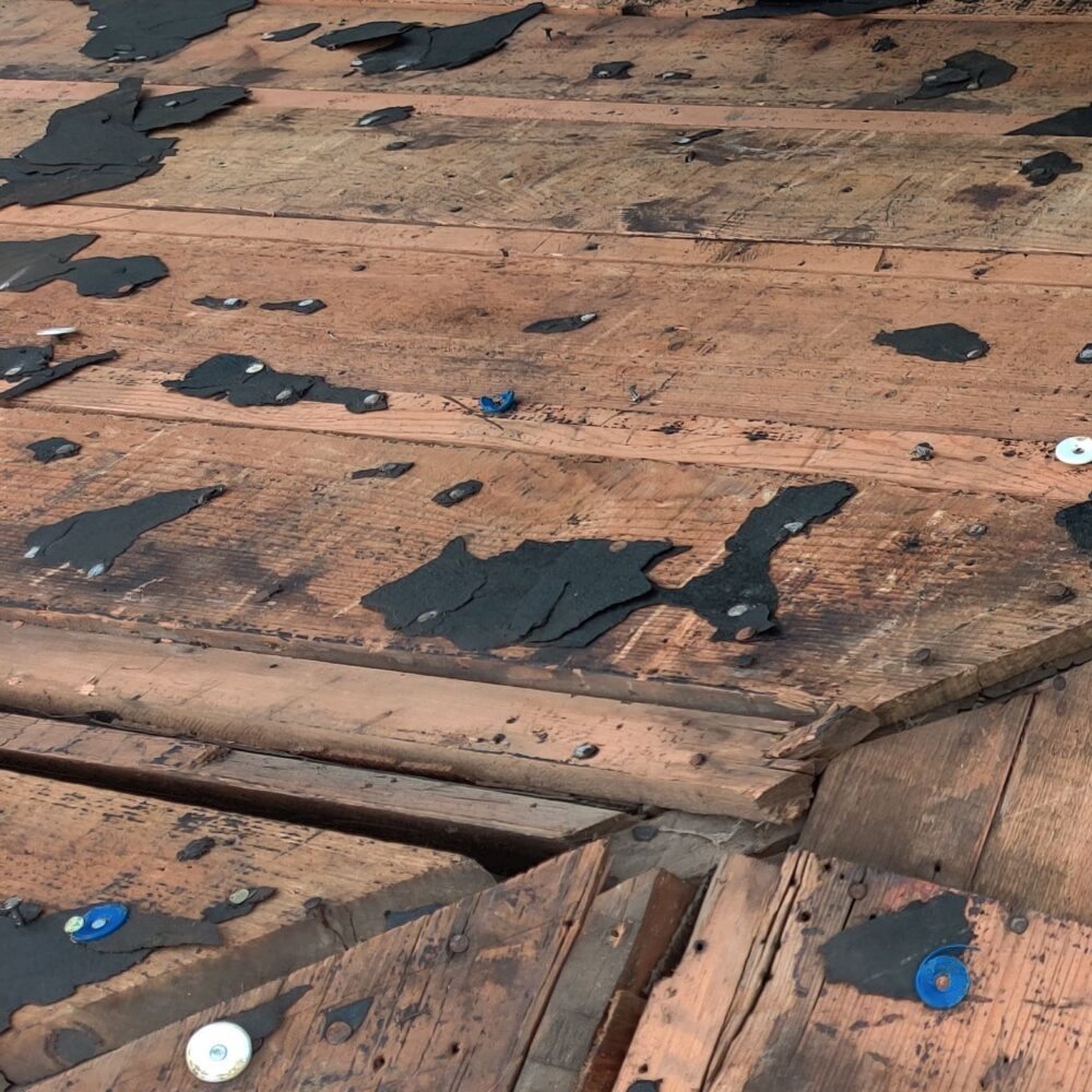 Damaged roof decking boards requiring repair before installing new shingles.